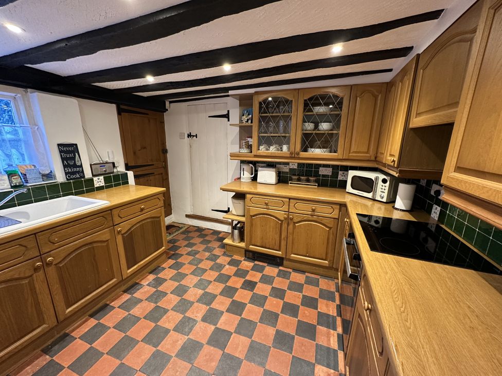 A kitchen with wooden cabinets and a sink at Hop Cottage in Buriton