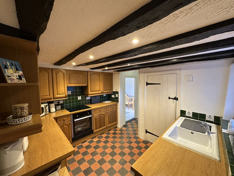 A kitchen with wooden cabinets and a sink at Hop Cottage Buriton