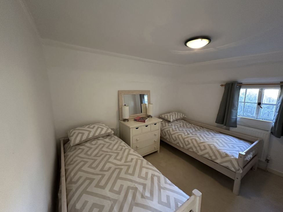A bedroom with two beds and a dresser at Hop Cottage in Buriton