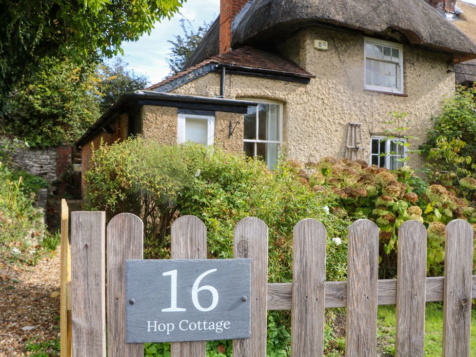A cottage with a thatched roof and garden at Hop Cottage in Buriton