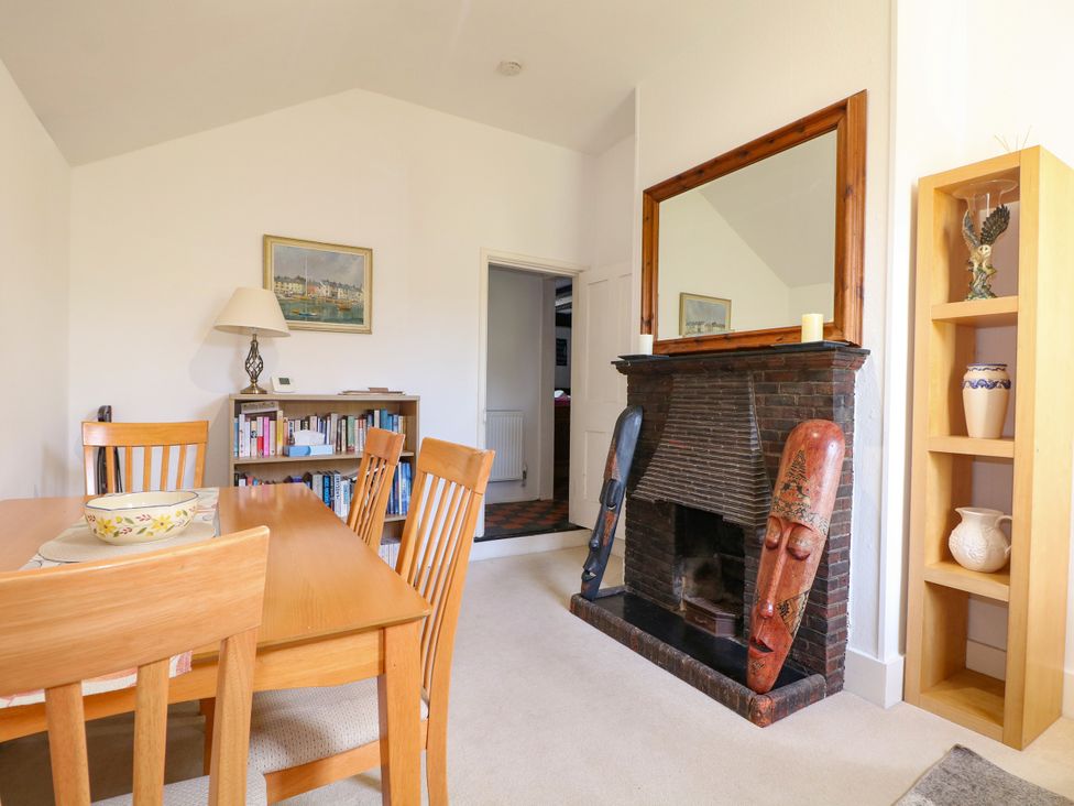 A dining room with a table and bookshelf at Hop Cottage in Buriton