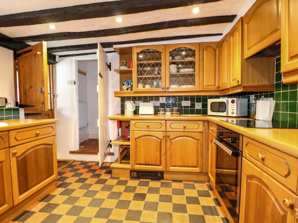 A kitchen with wooden cabinets and appliances at Hop Cottage Buriton