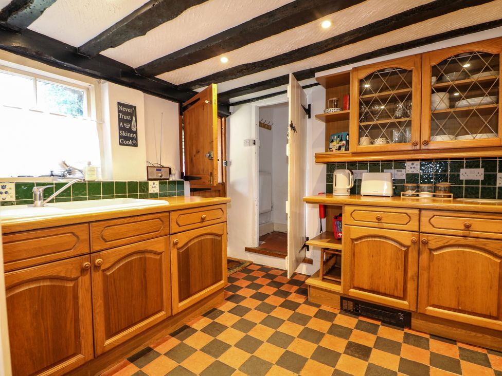 A kitchen with wooden cabinets and appliances at Hop Cottage in Buriton