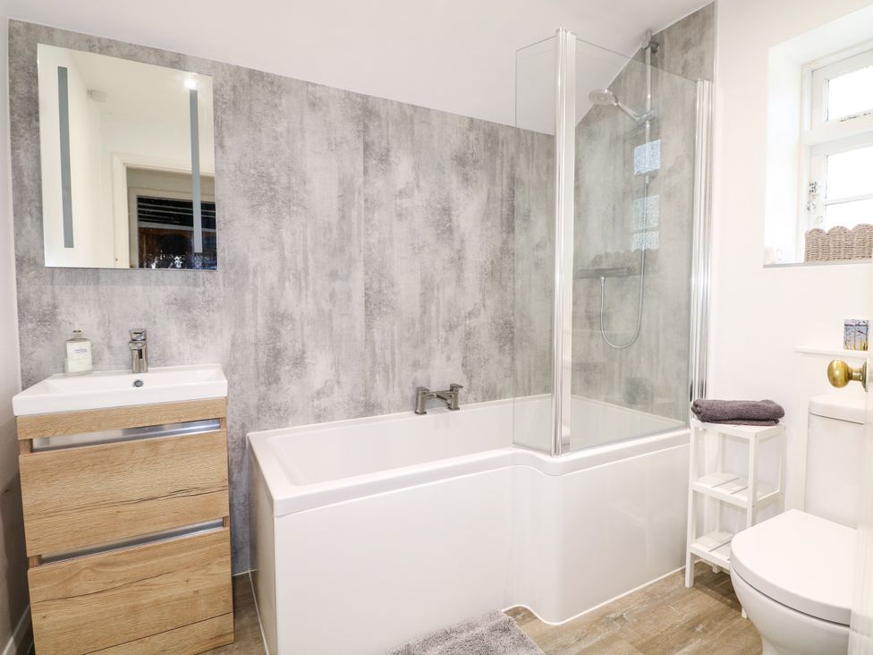 A bathroom with a bathtub, shower, and sink at Hop Cottage in Buriton