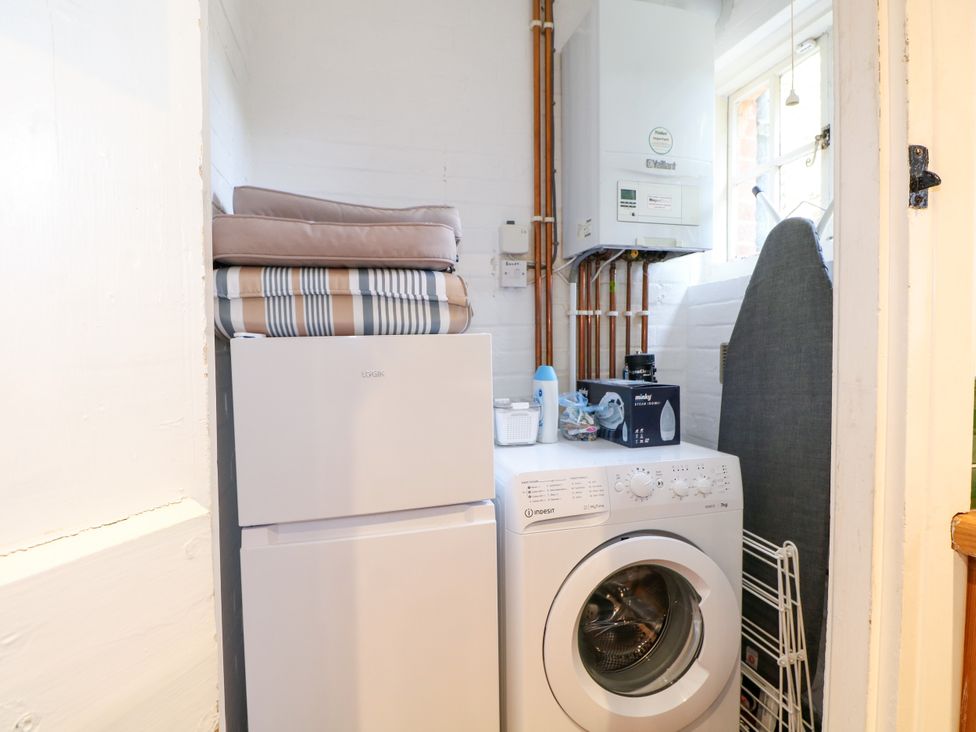 A laundry room with a washing machine and fridge at Hop Cottage in Buriton