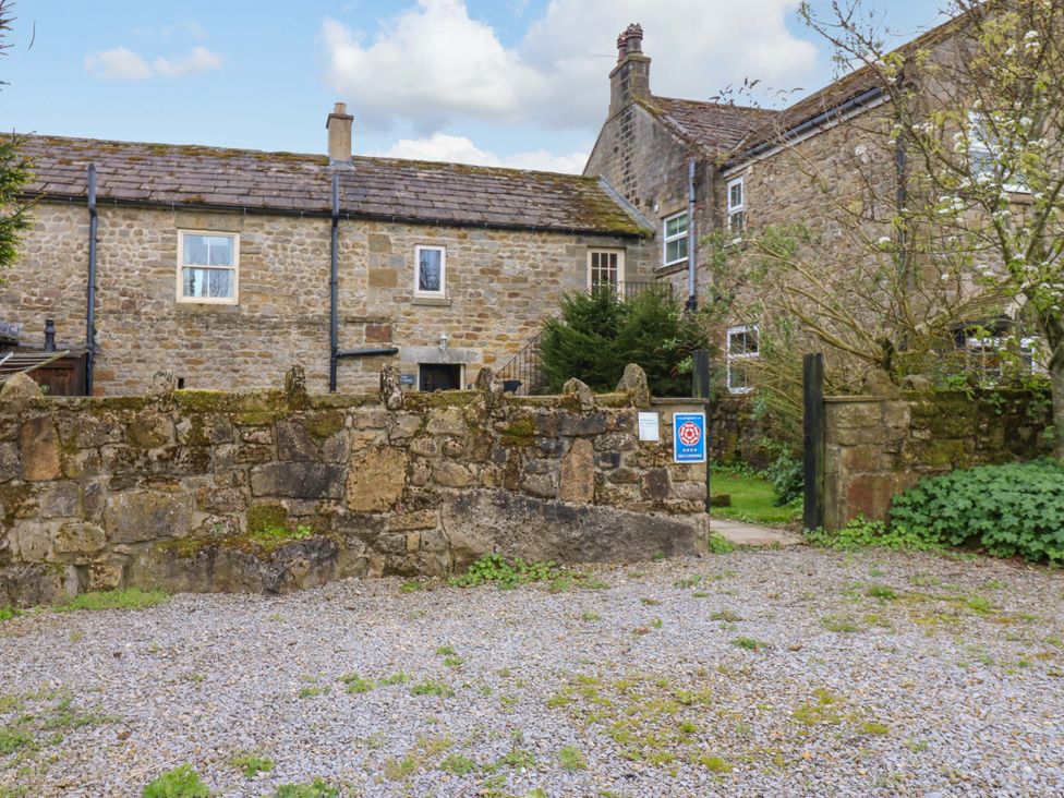 An outdoor area with a stone wall and gravel driveway at The Hay Barn in 