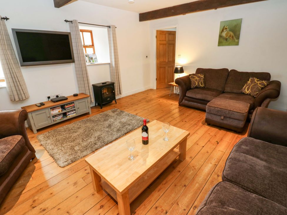 A living room with sofa armchair and television at The Hay Barn in 