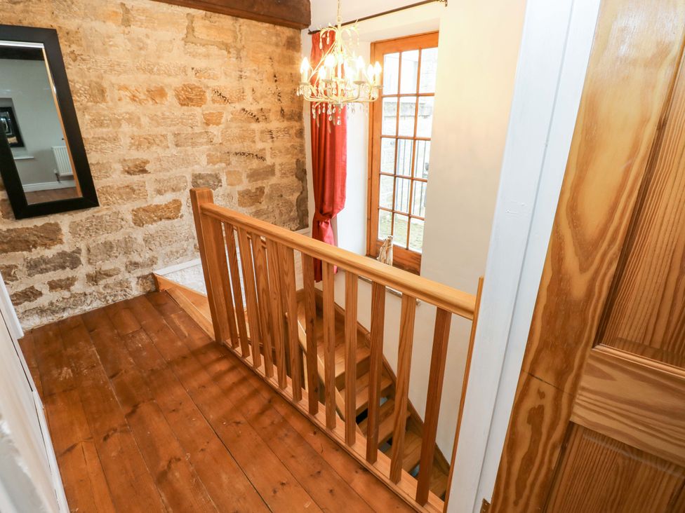 A stairway with a wooden railing and window at The Hay Barn