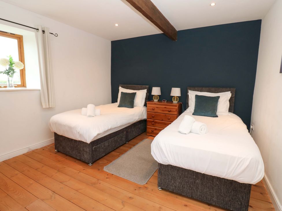 A bedroom with two single beds and a window at The Hay Barn in 