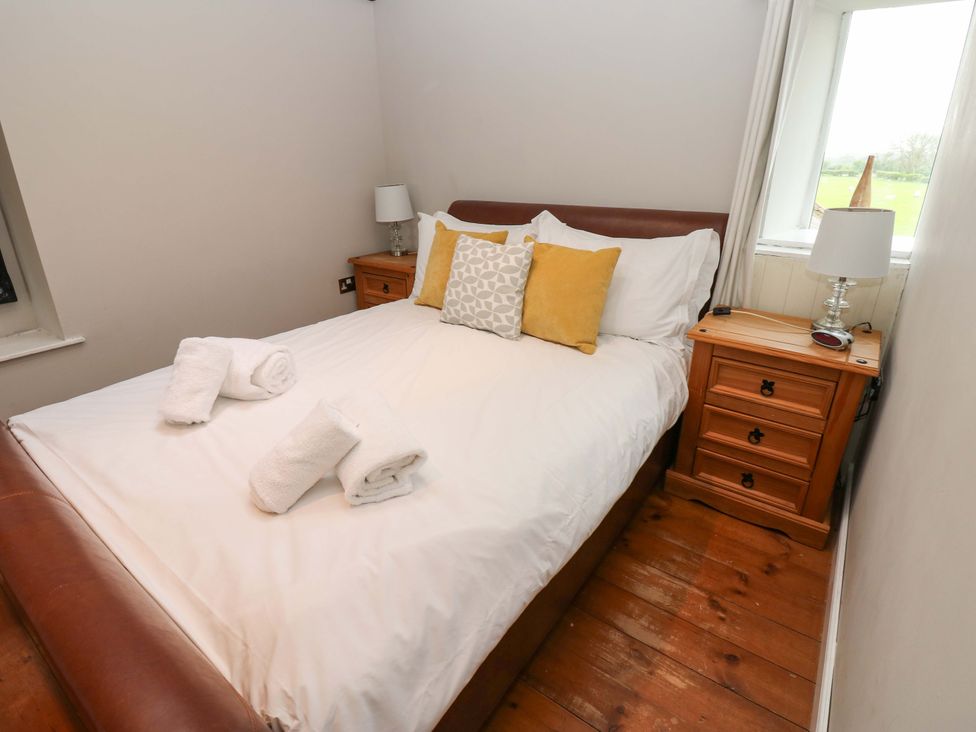A bedroom with a bed and nightstand at The Hay Barn