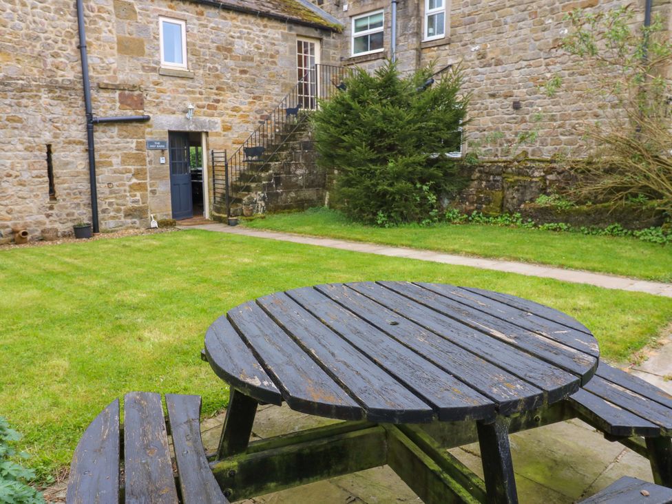 A garden with a wooden table and benches at The Hay Barn in 