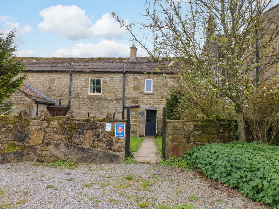 An outdoor view of a stone building with a pathway and gate at The Hay Barn 