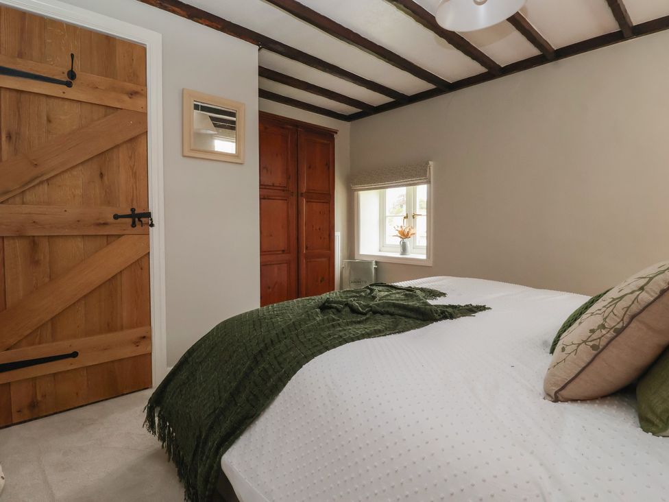 A bedroom with a bed and wooden door at Maple Tree Cottage Knaresborough