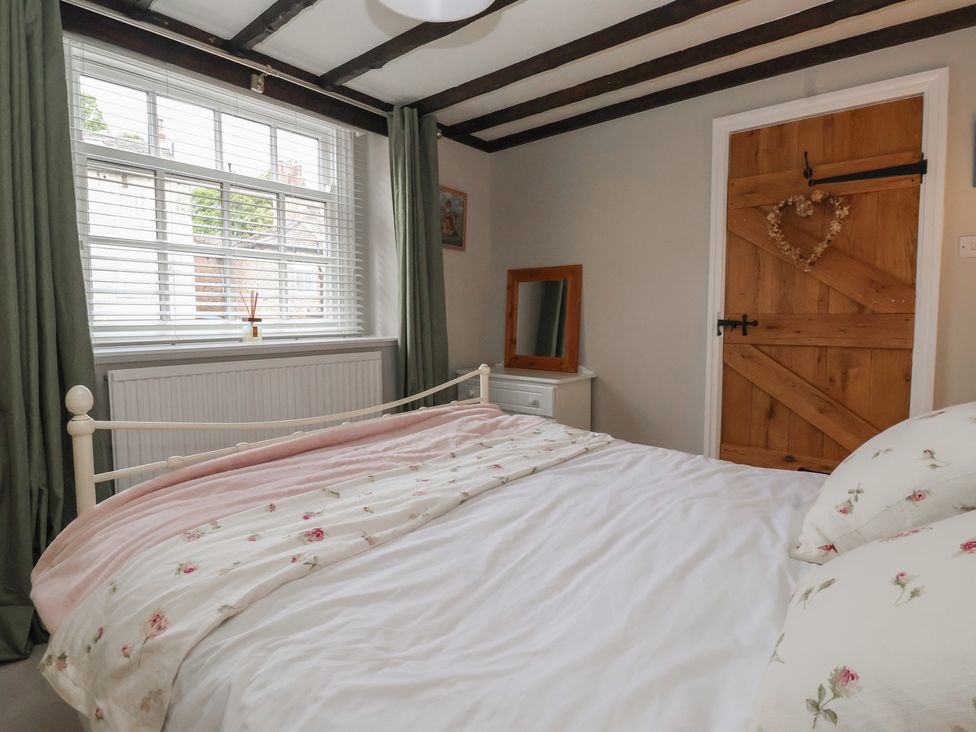A bedroom with a bed and mirror at Maple Tree Cottage in Knaresborough