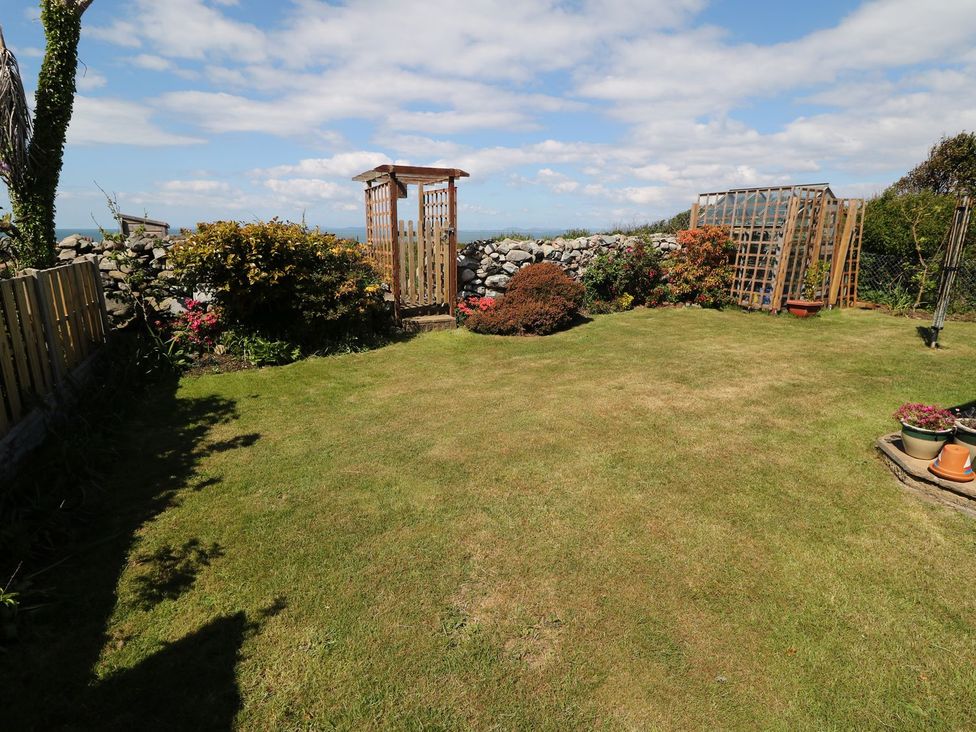 A garden with grass, flower beds, and trellis structures at Goetra