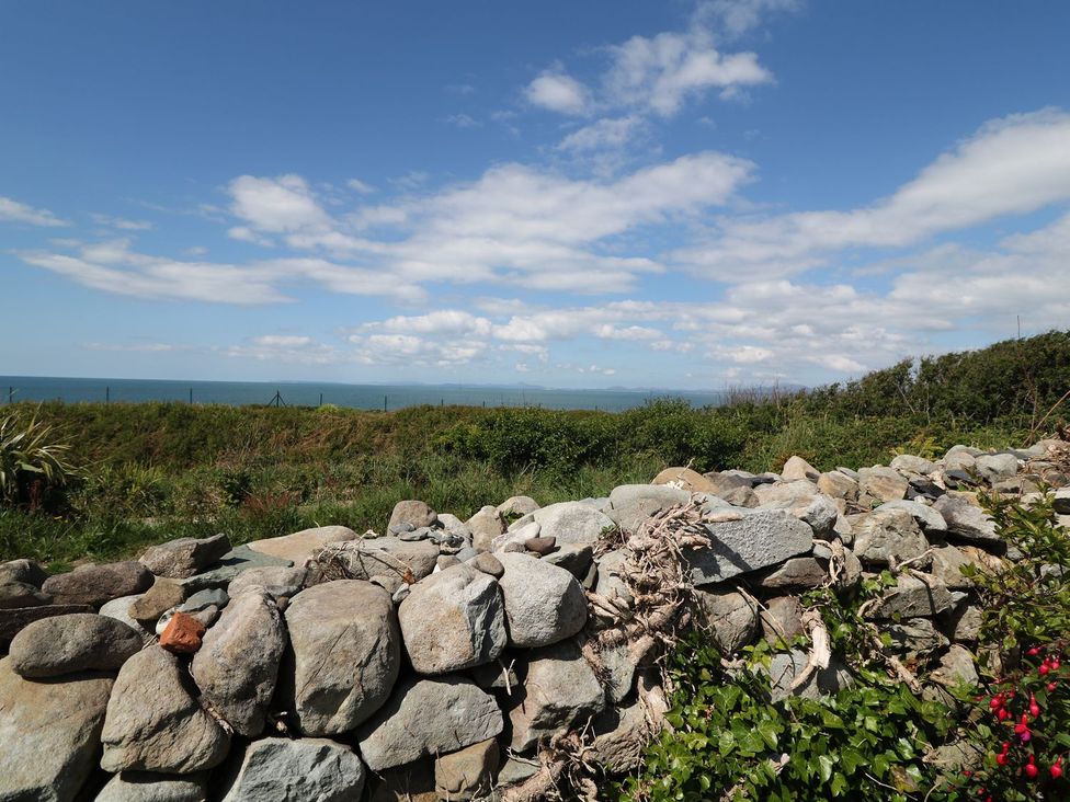A view of the sea and grassland with a stone wall at Goetra