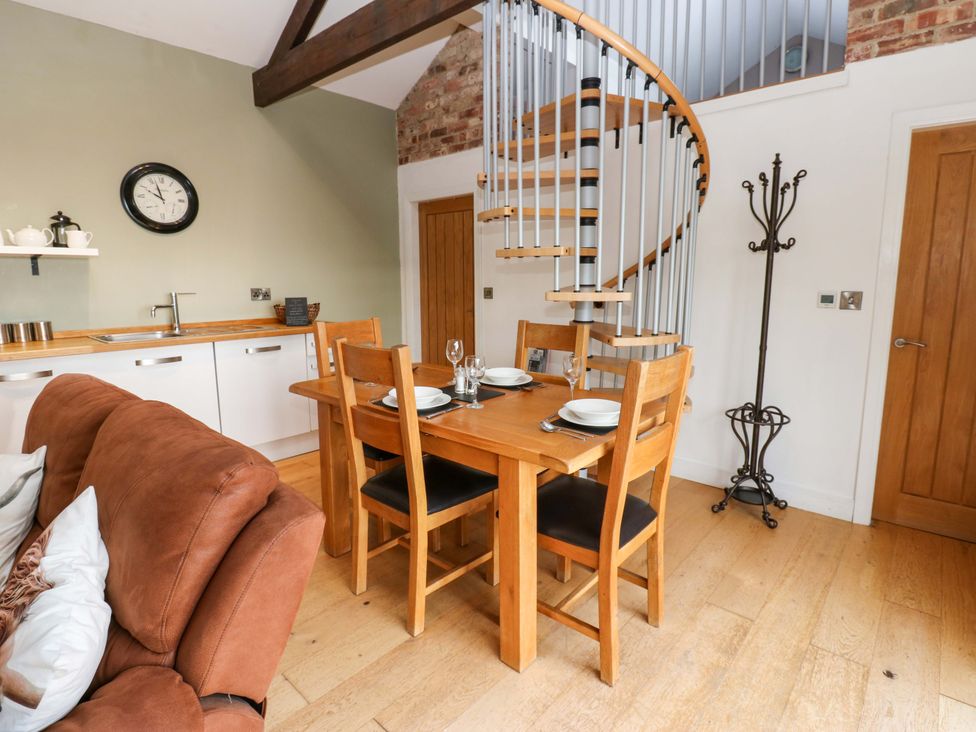 A dining area with table and spiral staircase at The Warren Barn in Kirkby Malzeard