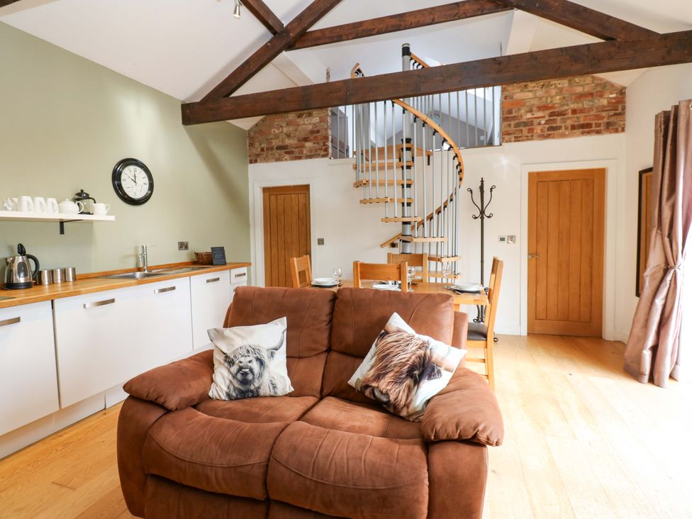 A living room with a sofa and dining area at The Warren Barn in Kirkby Malzeard