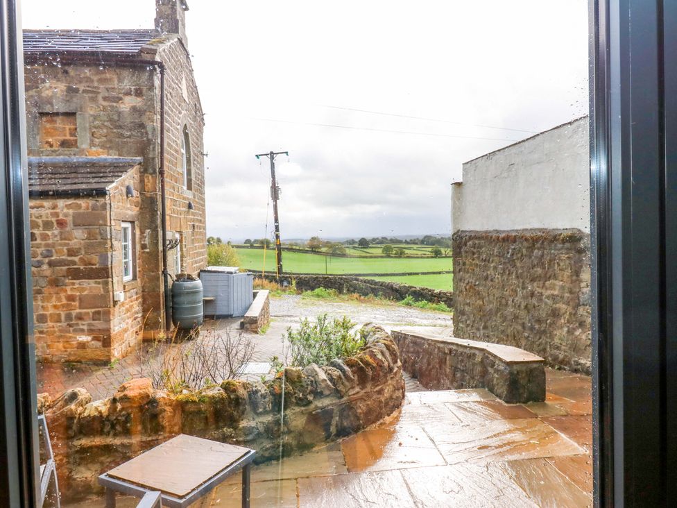 A view of a stone wall and garden area with a table at The Warren Barn in Kirkby Malzeard