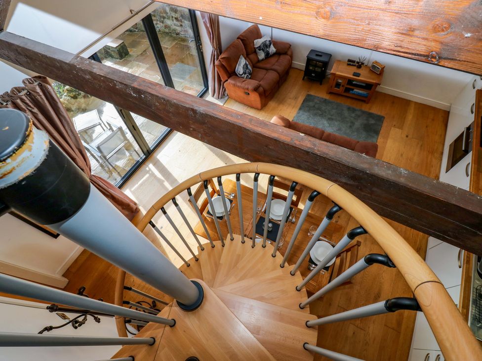 A living room with a spiral staircase and sofa at The Warren Barn in Kirkby Malzeard