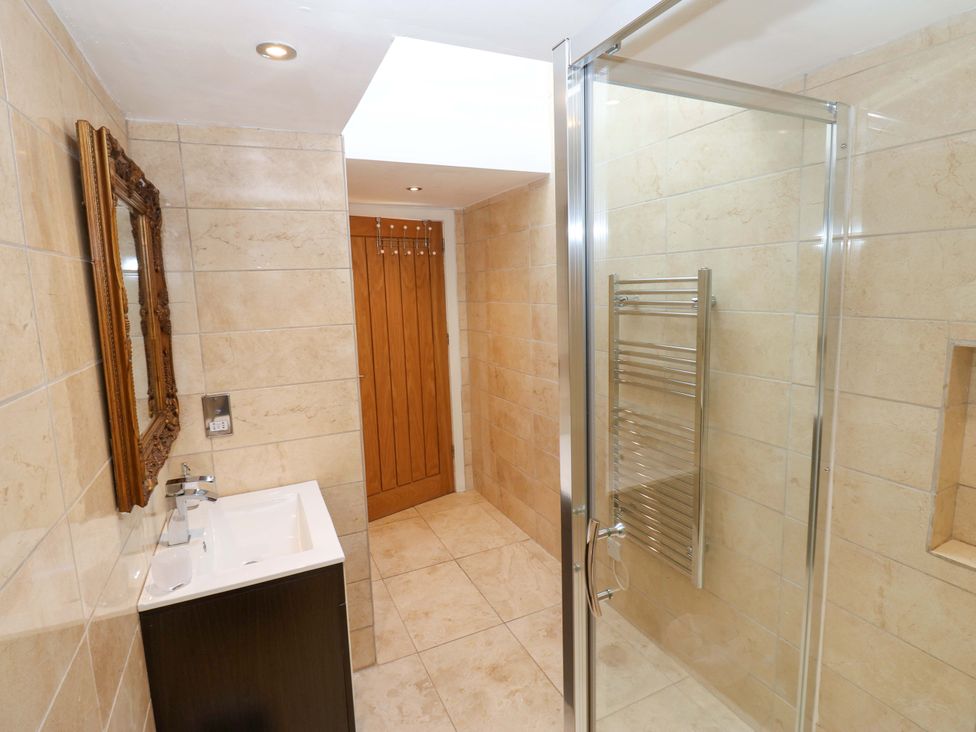 A bathroom with a sink, mirror, and shower at The Warren Barn in Kirkby Malzeard