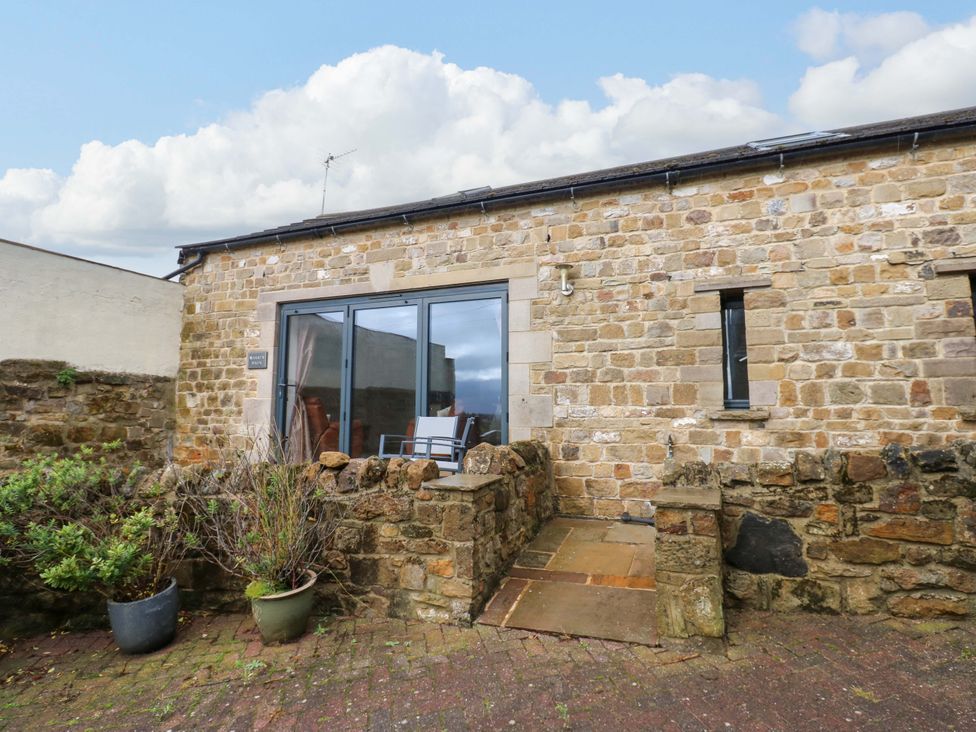 An outdoor area with stone wall and plants at The Warren Barn in Kirkby Malzeard