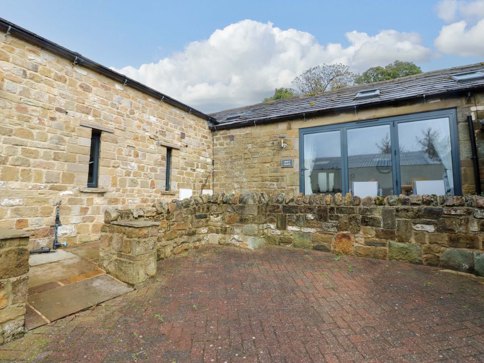 An outdoor area with a stone wall and windows at The Holt Barn in Kirkby Malzeard
