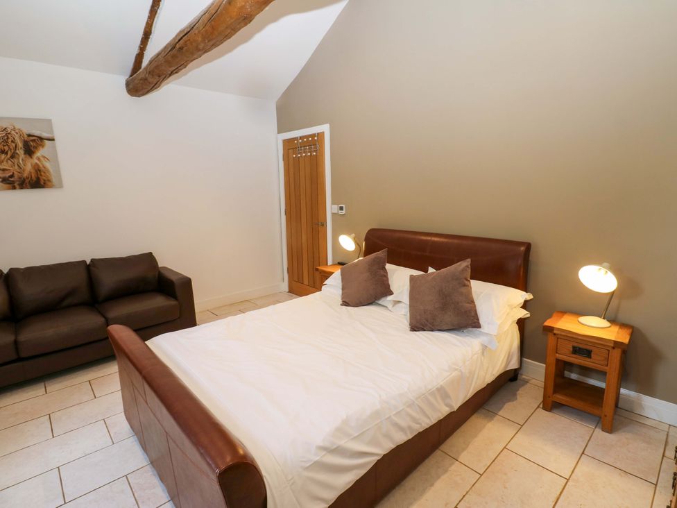 A bedroom with a bed and sofa at The Holt Barn in Kirkby Malzeard