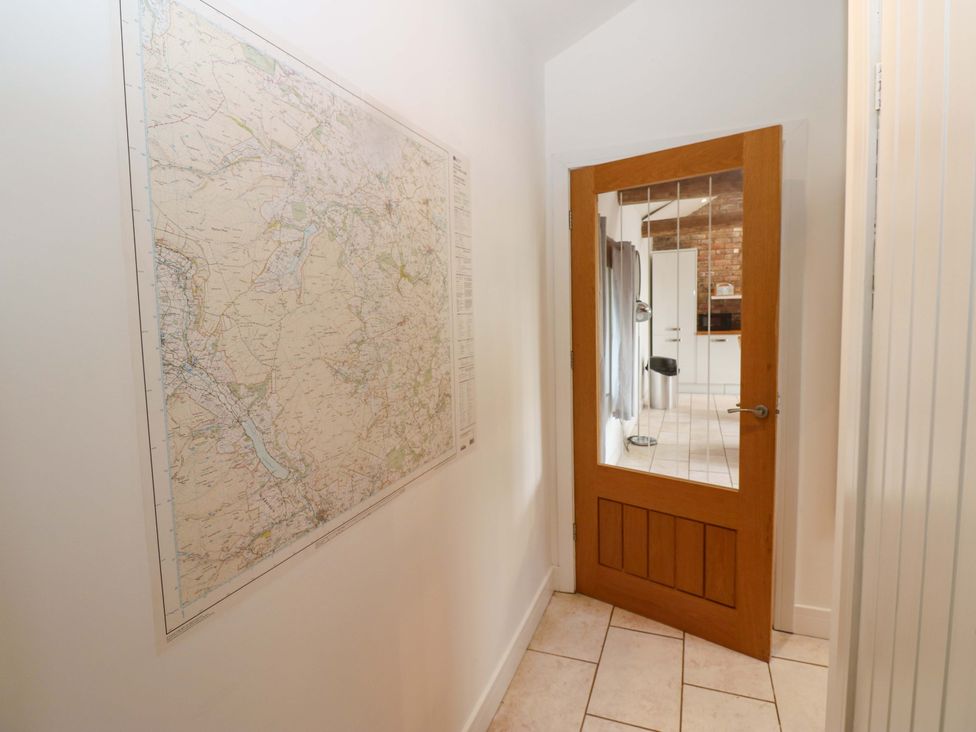 A hallway with a map on the wall and a wooden door at The Holt Barn in Kirkby Malzeard