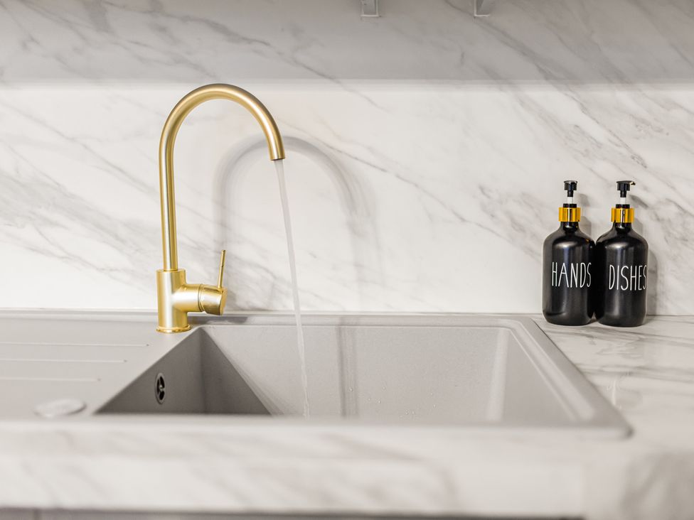 A kitchen sink with a gold faucet and soap dispensers at Central Vista Retreat Chester