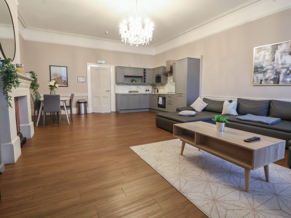 A living room with a grey sofa and a kitchen unit at Central Vista Retreat Chester