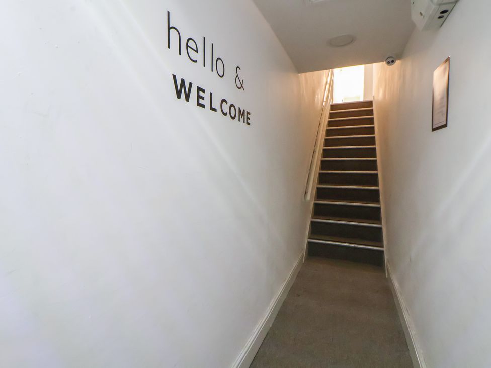 A hallway with a staircase and a welcome sign at Ravenswood Penthouse Chester