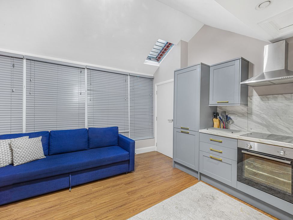 A kitchen with a blue sofa and grey cabinets at Kingsley Loft in Chester