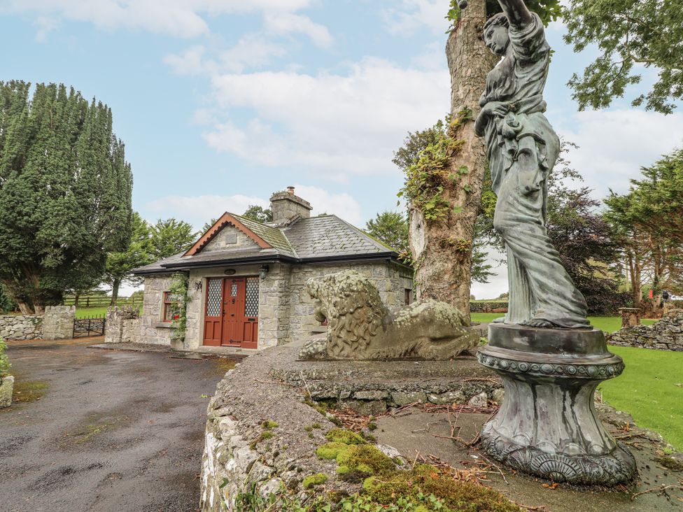 A stone cottage with a lion statue and a female statue at Coole Gate Lodge in Gort, County Galway