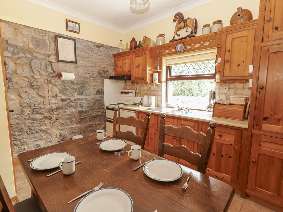 A kitchen with wooden cabinets and a dining table at Coole Gate Lodge, Gort, County Galway