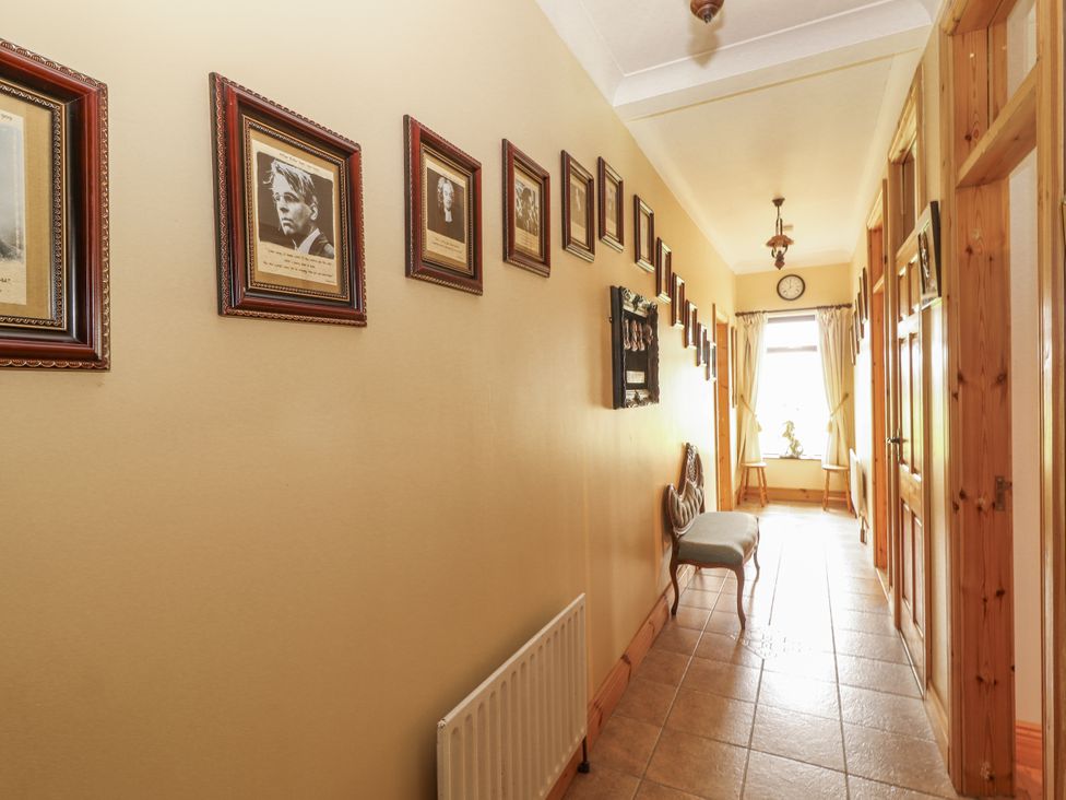 A hallway with framed photographs and a bench at Coole Gate Lodge, Gort, County Galway