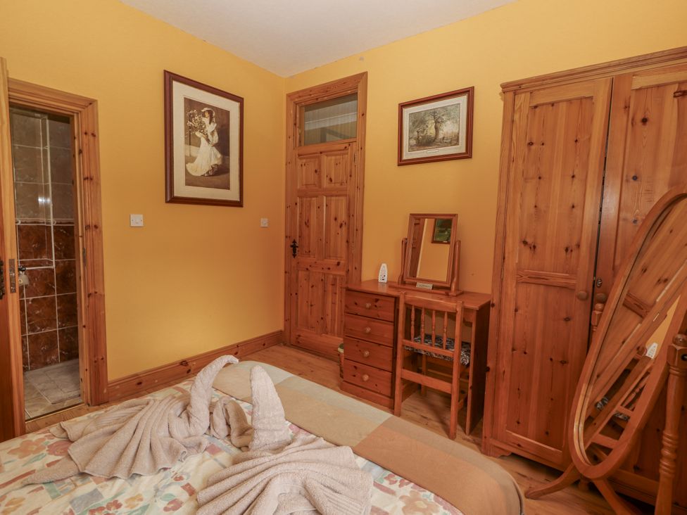 A bedroom with a bed and furniture at Coole Gate Lodge, Gort, County Galway