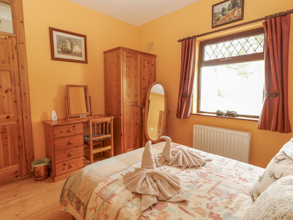 A bedroom with a bed and furniture at Coole Gate Lodge in Gort, County Galway
