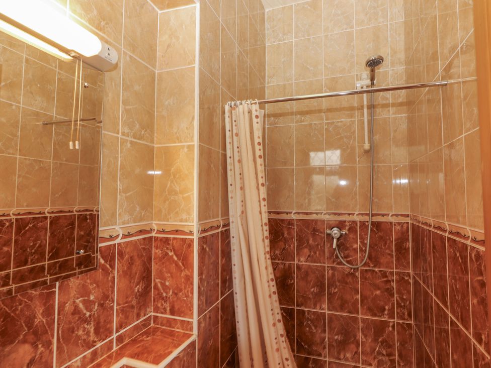 A shower area with a curtain and mirror at Coole Gate Lodge, Gort, County Galway