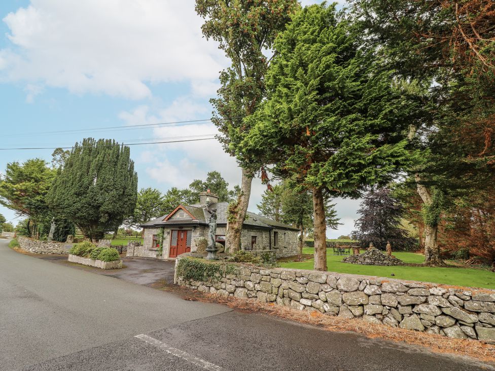 A house with stone walls and trees on the exterior at Coole Gate Lodge in Gort, County Galway