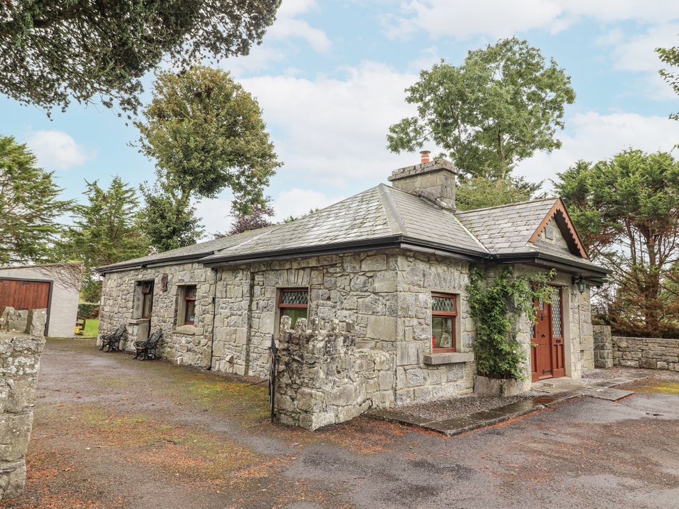 A stone cottage with trees in the background at Coole Gate Lodge in Gort, County Galway