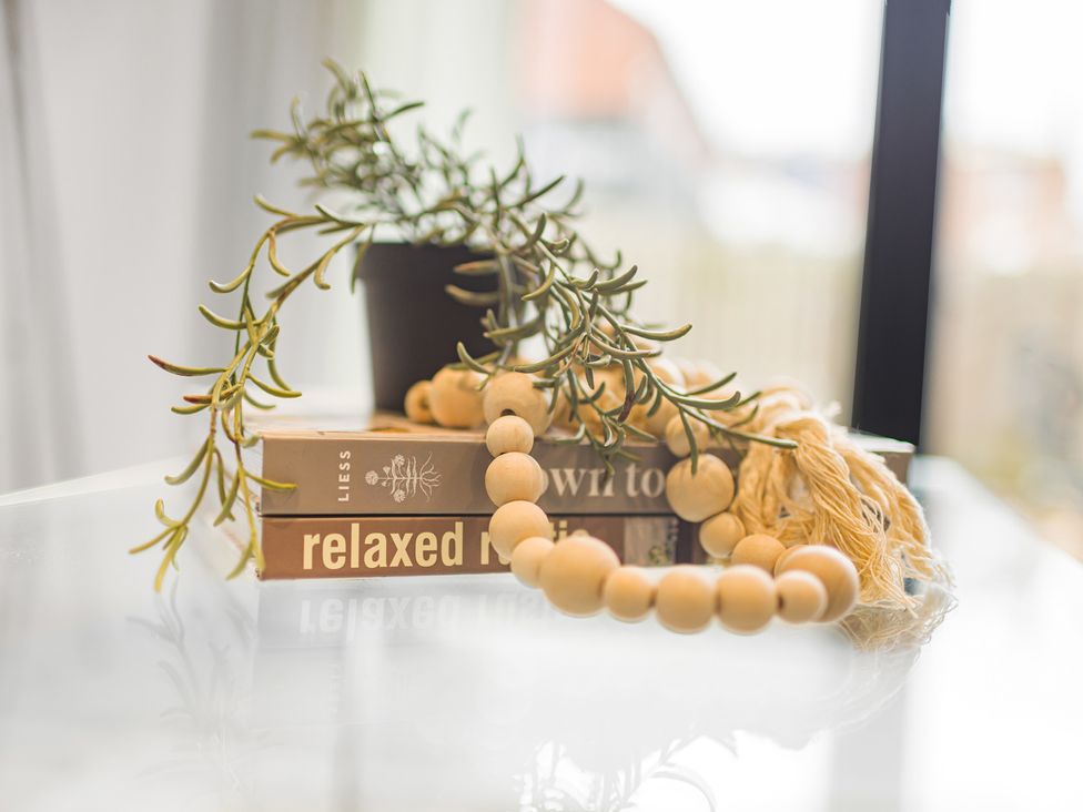 A tabletop with books, a plant, and wooden beads at Eastgate Suite, Chester