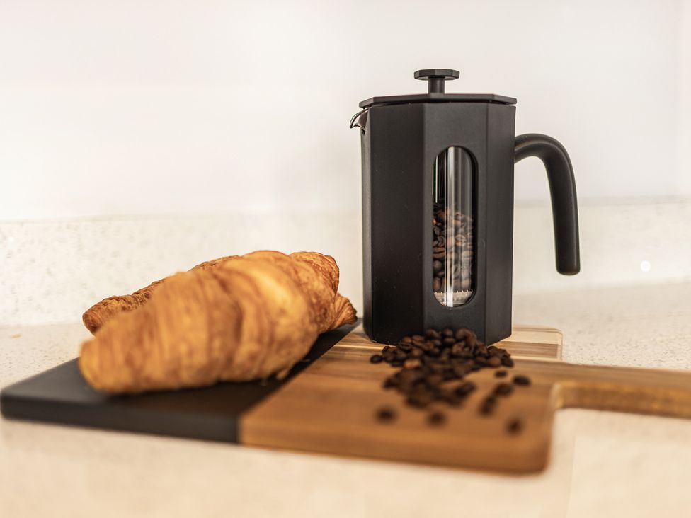 A coffee maker with croissants and coffee beans on a cutting board at Newland Suite Chester