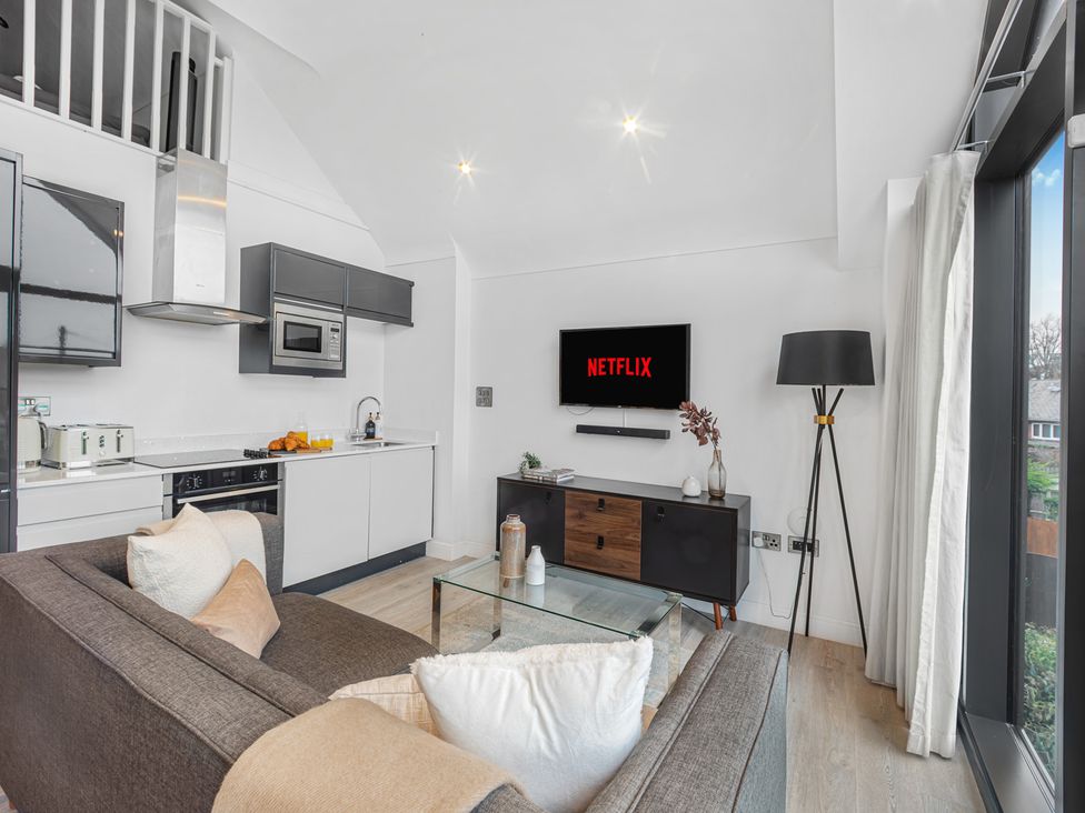 A living room with a television and kitchen cabinets at Mulberry Apartment in Chester