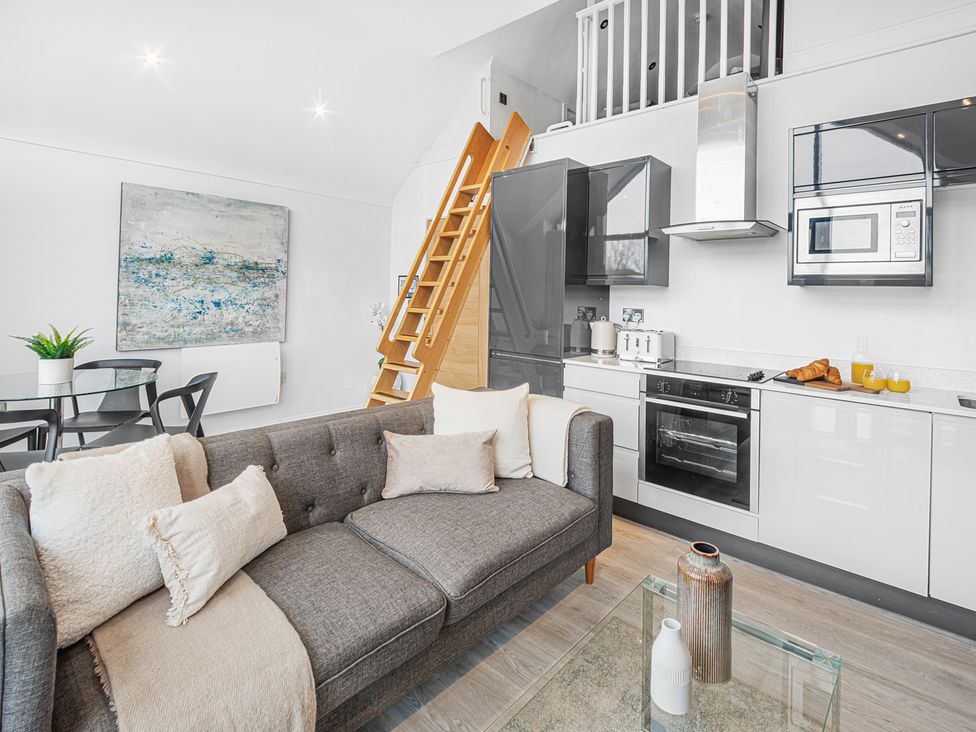 A living room with a sofa and kitchen area at Mulberry Apartment in Chester