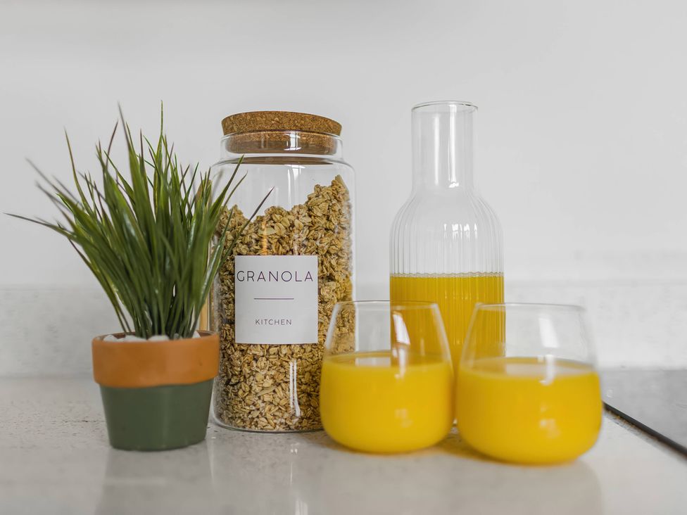 A kitchen countertop with a granola jar, orange juice carafe and glasses at Grosvenor Apartment in Chester