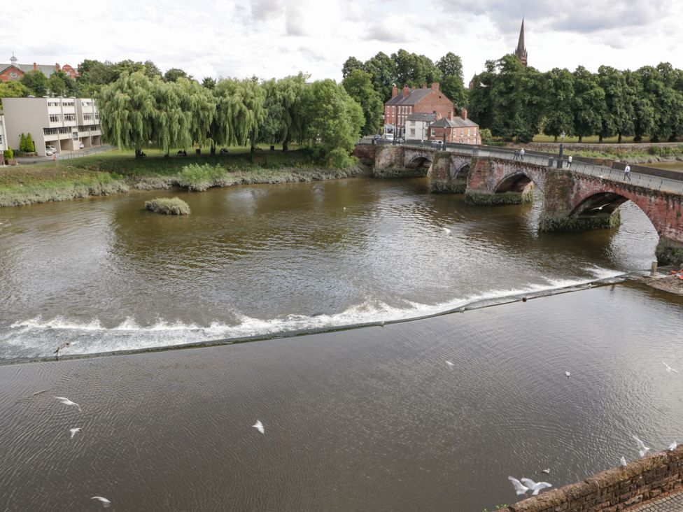 A view of a river with a bridge and trees at Grosvenor Apartment in Chester