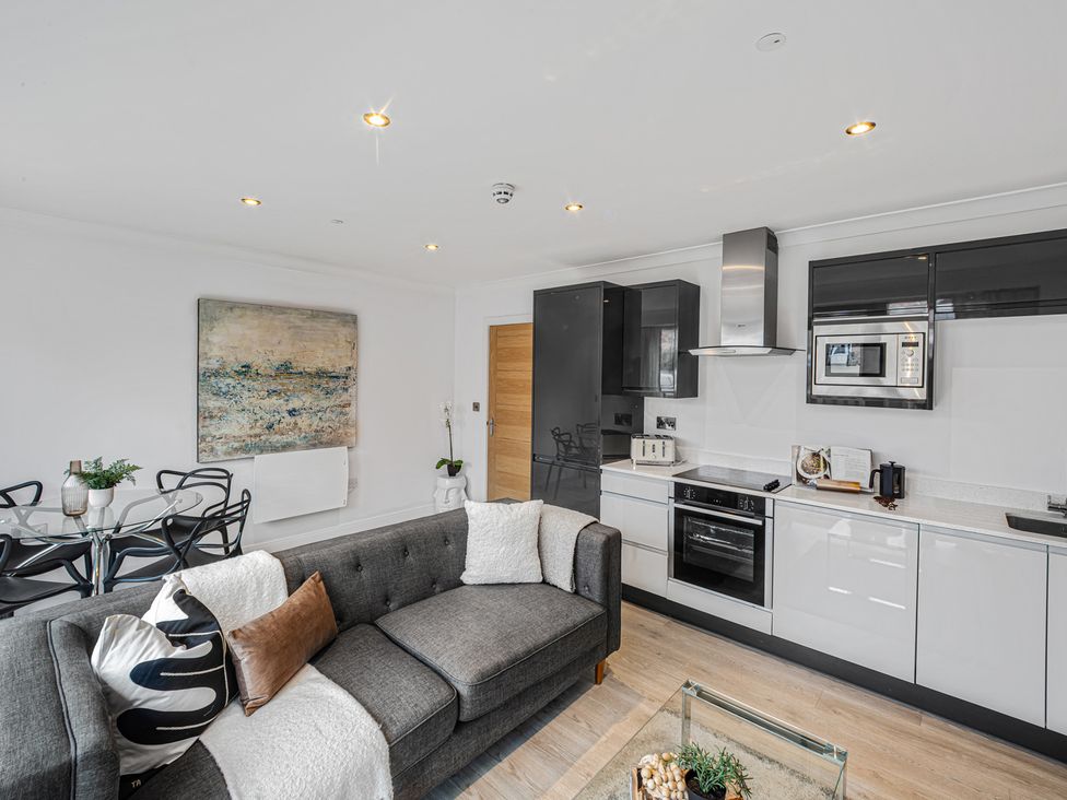 A living room with a sofa and kitchen area at York Suite in Chester