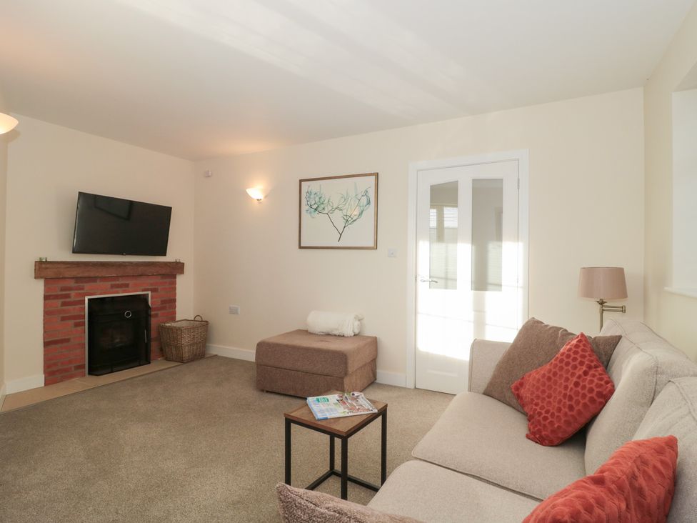 A living room with a television and fireplace at Wellinghill Cottage at Wellinghill House in Charlton Kings