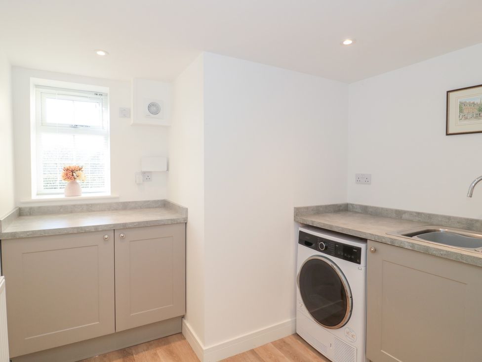 A laundry room with a washing machine and sink at Wellinghill Cottage at Wellinghill House Charlton Kings